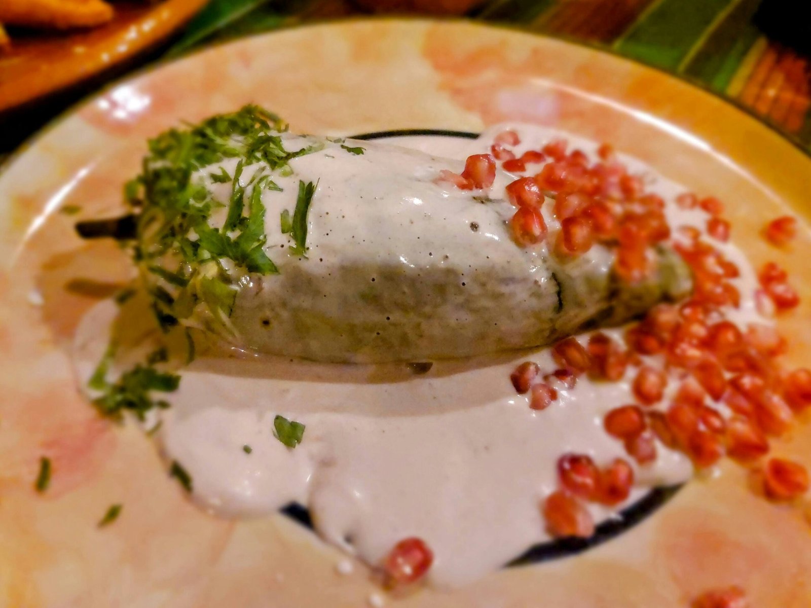 A stuffed chile covered with walnut sauce and pomegranate seeds