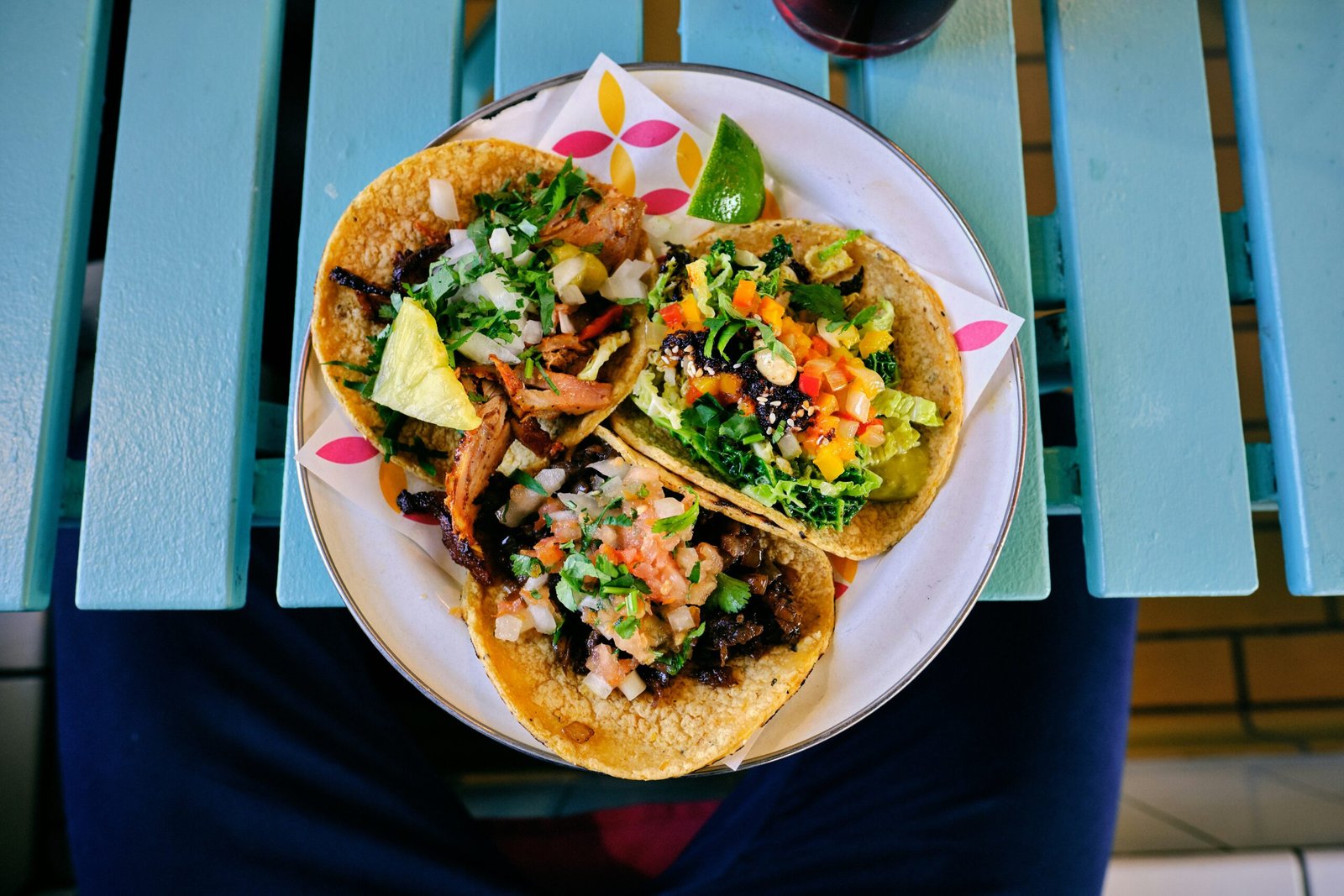 Three tacos with assorted fillings and garnishes